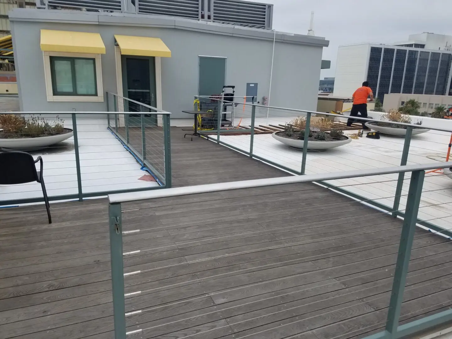 A man in an orange shirt is on the roof of a building.