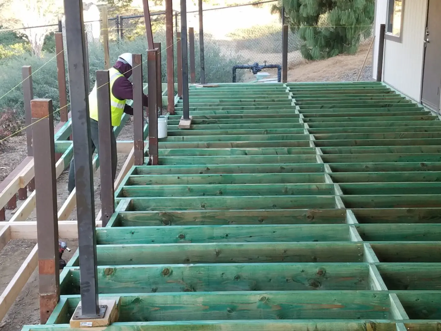 A person in yellow vest and green jacket standing on stairs.