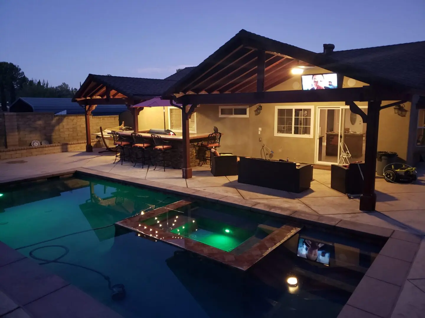 A pool with an entertainment center and patio.