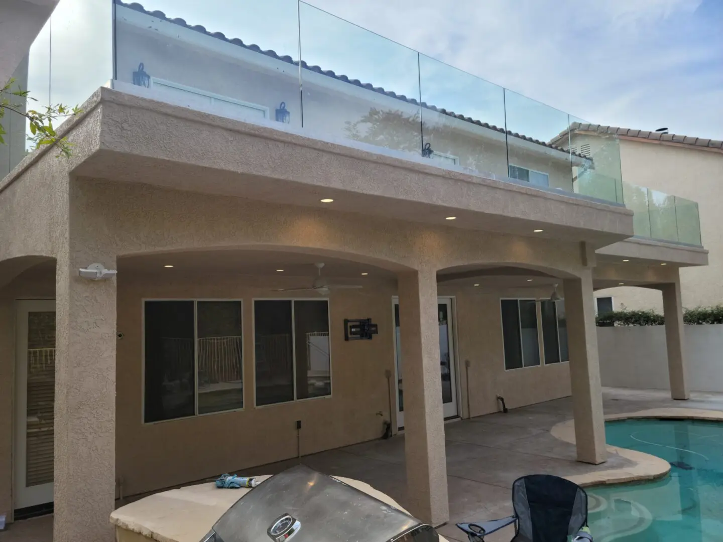 A pool and patio area with a glass railing.