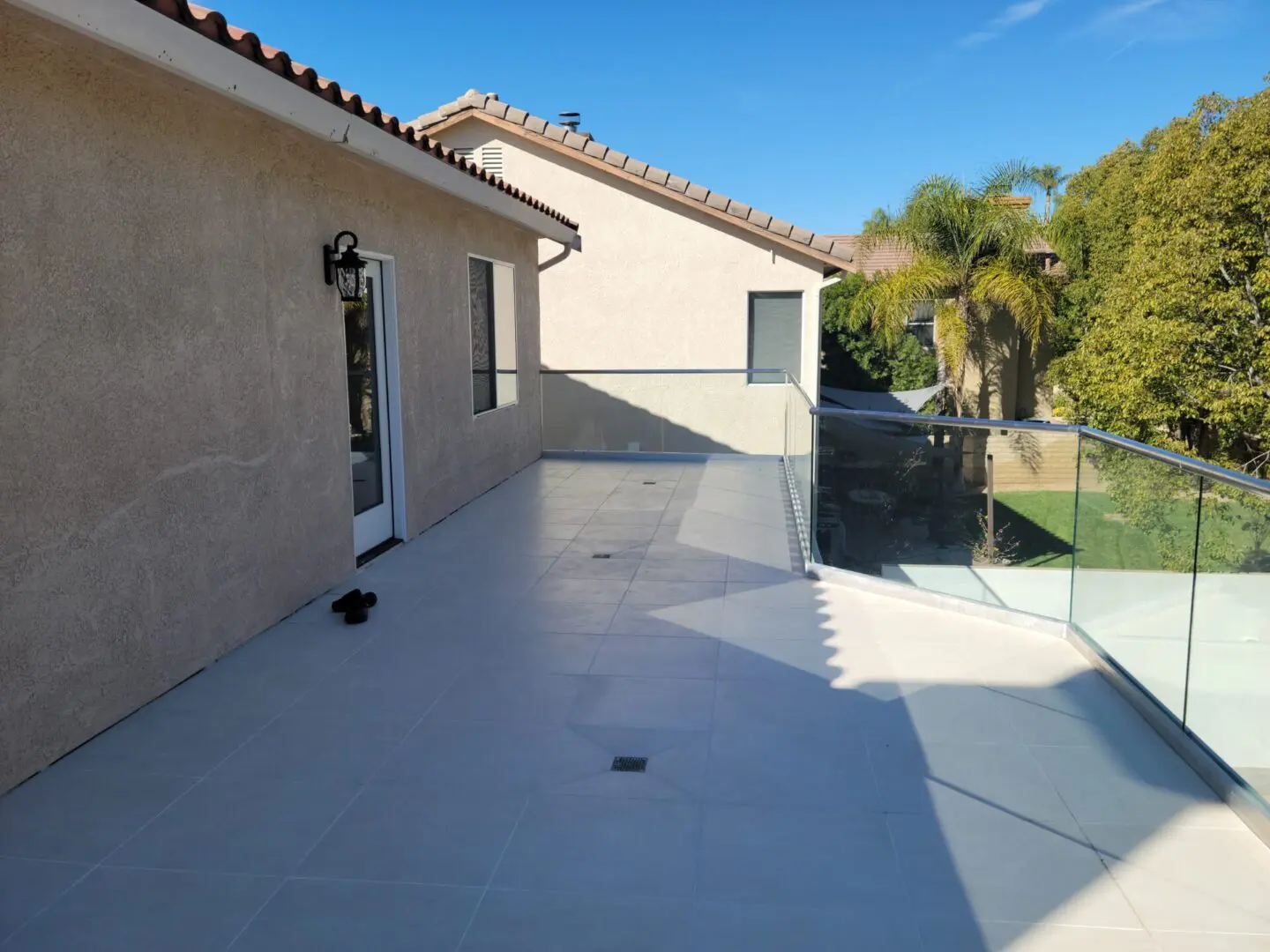 A patio with a glass fence and palm trees.