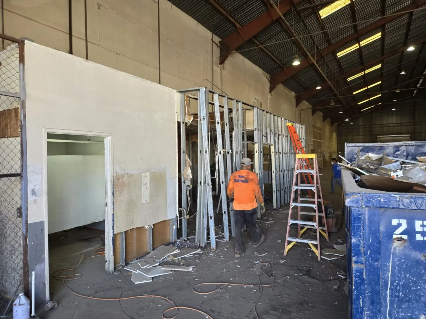 A man in an orange shirt is working on the wall.